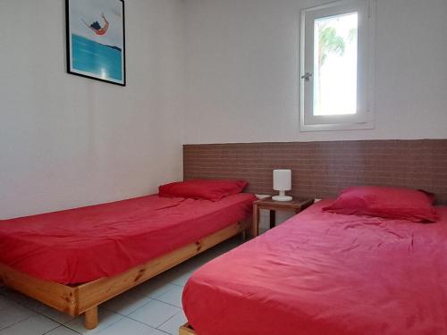 - 2 lits dans une chambre avec des draps rouges et une fenêtre dans l'établissement Bel appartement 2 pièces, 4 pers, Port Argelès, plage et commerces proches, parking inclus - FR-1-776-78, à Argelès-sur-Mer