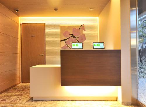a reception desk in a lobby with two monitors on it at Rakuten STAY x Shamaison Osaka Dekijima Station in Osaka