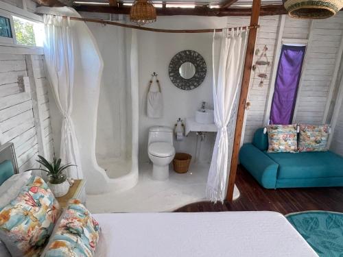 baño con aseo y sofá azul en Mio Mio Beach, en Barú