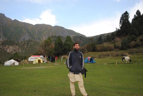 a man is standing in a field with tents at Rakaposhi Amin Hotel & Restaurant Pissan Hunza Nagar Gilgit Baltistan in Gilgit