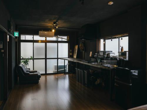 a dark room with a kitchen with a counter and windows at まちごとホテルLOOP 小林 in Makata