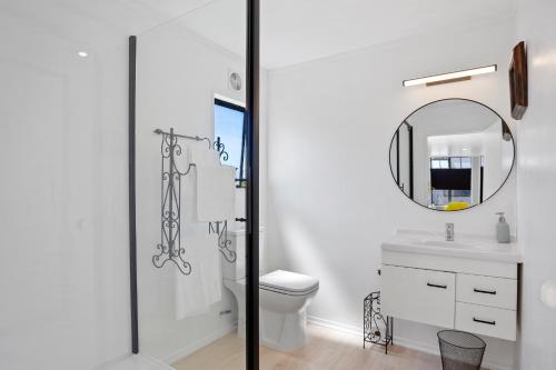 a white bathroom with a toilet and a mirror at Da Vics - Athenree Holiday Home in Katikati