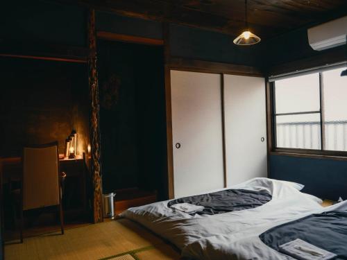 a bedroom with a bed and a window at まちごとホテルLOOP 小林 in Makata