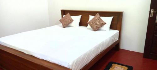 una camera da letto con letto, lenzuola e cuscini bianchi di Eastree villa midigama a Midigama East