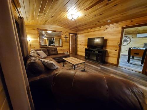 a living room with a couch and a flat screen tv at Luxury Cabin w/ Game Room & Hot Tub at Cave Run Lake in Wellington