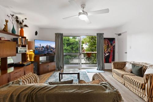 a living room with a couch and a tv at Mid-Century Morningside 2-Bed Apartment in Brisbane