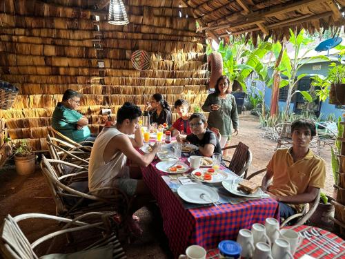 a group of people sitting around a table eating food at Ava garden backpackers in Mto wa Mbu