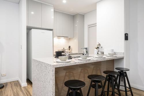a kitchen with a counter with bar stools at Zetland near Shops & Train with Gym&Pool for 6ppl in Sydney