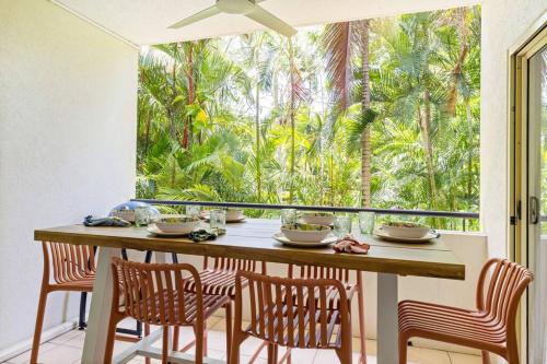 a dining room with a table and chairs and a large window at Laidback Resort Living at Central Plaza Poolside in Port Douglas