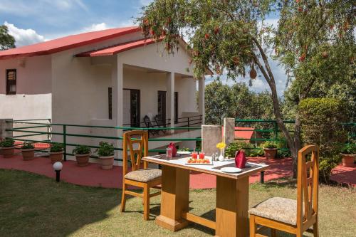a table and chairs in front of a house at Binsar Eco Resort, Binsar - Uttarakhand in Hawālbāgh