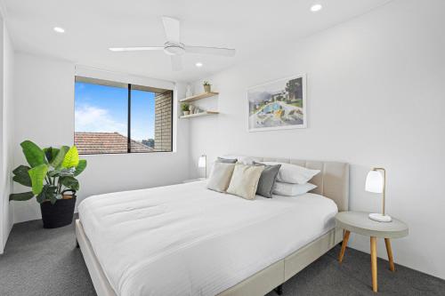a white bedroom with a large bed and a window at Spacious 1-Bed in the Heart of Teneriffe in Brisbane