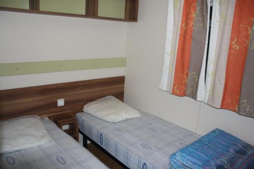 une chambre avec deux lits et une fenêtre dans l'établissement le Camping Des 3 Lacs, à Belmont-Tramonet