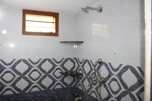 uma casa de banho com uma parede em azulejo preto e branco em Pallavi Homestay em Honāvar