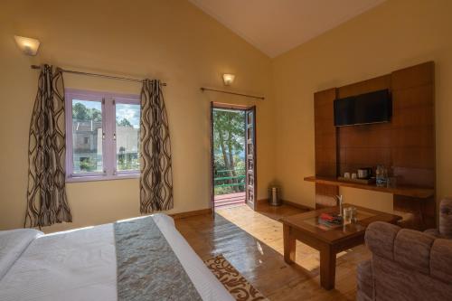 a living room with a bed and a couch and a tv at Binsar Eco Resort, Binsar - Uttarakhand in Hawālbāgh