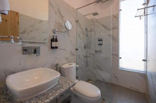 a white bathroom with a toilet and a sink at Binsar Eco Resort, Binsar - Uttarakhand in Hawālbāgh