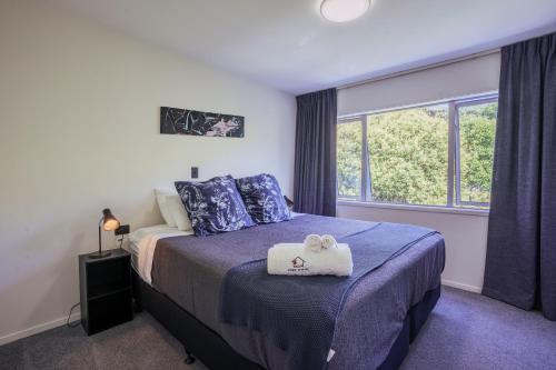 a bedroom with a bed with blue sheets and a window at Auckland City Escape Modern Home with Spa Pool in Auckland