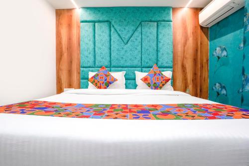 a bedroom with a white bed with a colorful headboard at FabExpress A1 Residency in Ahmedabad