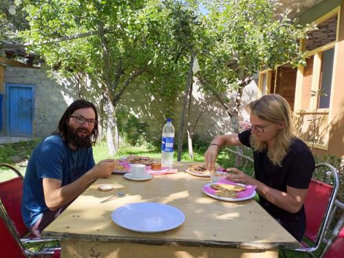 a man and woman sitting at a table eating food at Rakaposhi Amin Hotel & Restaurant Pissan Hunza Nagar Gilgit Baltistan in Gilgit