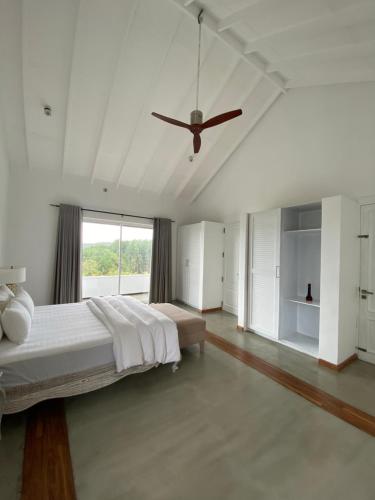 a white bedroom with a bed and a ceiling fan at Benito Bungalow by The Serendipity Collection in Haputale