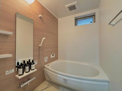 a bathroom with a tub and a shower with a window at Neighbor's Hotel 楽々園 in Hiroshima