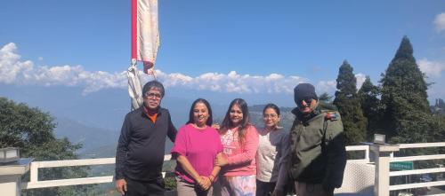 a group of people posing for a picture in front of a mountain at Zingo's Home Stay in Darjeeling