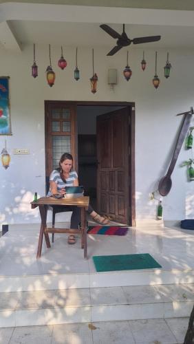 a woman sitting at a table in front of a house at ABRU'S Holidays International in Alleppey