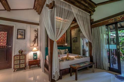 a bedroom with a bed with curtains and a table at KTS Balinese Villas in Canggu