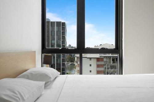 a bed with two pillows in front of a window at Spaciously Bright 1-Bed Apartment in Brisbane