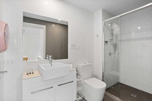 a bathroom with a toilet and a sink and a shower at Spaciously Bright 1-Bed Apartment in Brisbane
