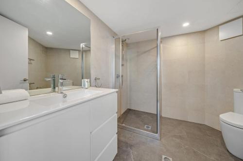 y baño con aseo, lavabo y ducha. en Central 2-bed Apartment with Pool, Gym and Spa, en Canberra