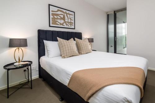 a bedroom with a large white bed and a lamp at Executive Balcony Apartment in Central Canberra in Canberra