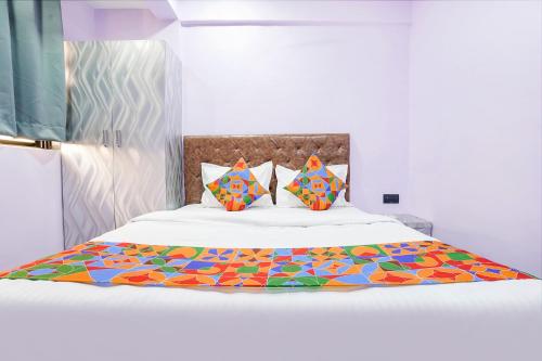 Un dormitorio con una cama blanca con sábanas y almohadas coloridas. en FabExpress Kirtiraj, en Panvel