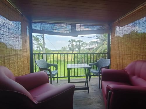 Habitación con sillas, mesa y balcón. en Andorra Tourist Resort Anuradhapura en Anuradhapura