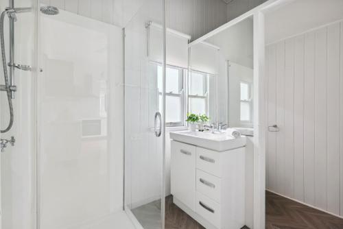 y baño blanco con lavabo y ducha. en Gorgeous 3-Bed Family Home by Oxenham Park & Shops en Brisbane