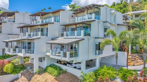 einen Luftblick auf ein weißes Apartmenthaus mit Palmen in der Unterkunft Whitsunday Reflections in Airlie Beach