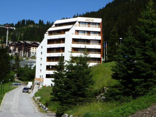a white building on a hill next to a road at Résidence Arche - Studio pour 4 Personnes 14 in Flaine