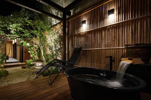 a bath tub on a wooden deck with a fountain at 瀬戸内サウナホテル月 in Takamatsu