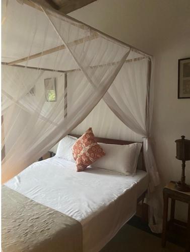 a bedroom with a canopy bed with white sheets and pillows at Emel's Retreat in Busse