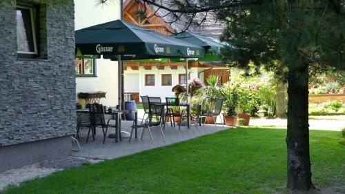 eine Terrasse mit Tischen, Stühlen und einem Sonnenschirm in der Unterkunft Gasthof zur Gams in Donnersbachwald