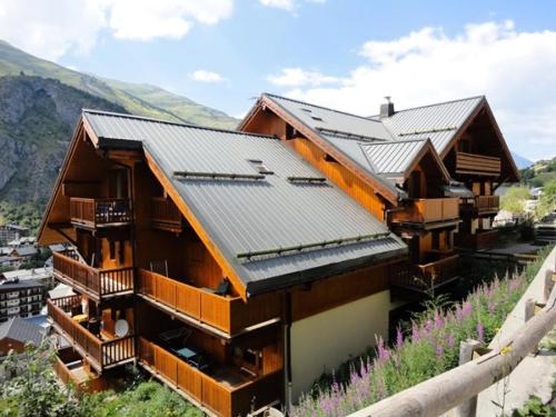 uma casa de madeira com telhado de metal em Résidence Gentiane Hameau De La Vallee D'or - 2 Pièces pour 4 Personnes 84 em Valloire