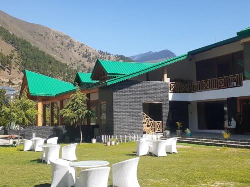 a group of white tables and chairs in front of a building at Smile Resort , Himachal Pradesh in Shamshi