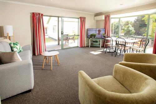 uma sala de estar com um sofá, cadeiras e uma mesa em Tāhuna Beach Holiday Park em Nelson