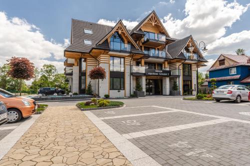 a large building with cars parked in a parking lot at Aparthotel Góralski Spa 2 in Białka Tatrzanska