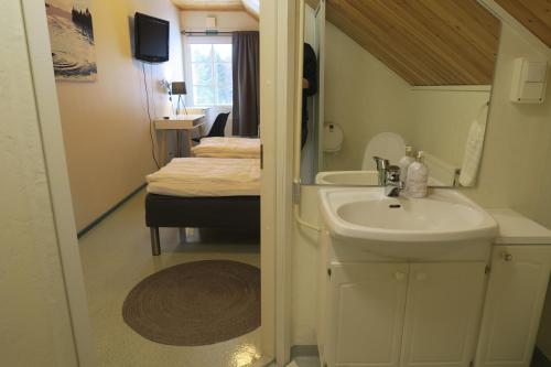 a bathroom with a sink and a bed in a room at Marjoniemi Camping in Hiidenniemi