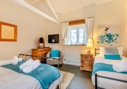 a bedroom with two beds and a desk and a window at Oriel Cottage in Bittadon