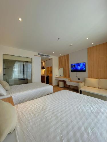 a large bedroom with two beds and a flat screen tv at Luna Apartment - Apec Mandala Phú Yên in Tuy Hoa