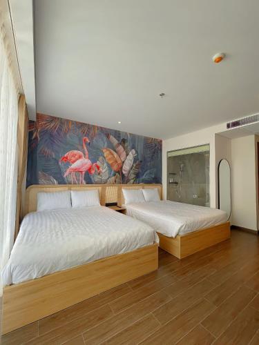 two beds in a room with a painting on the wall at Luna Apartment - Apec Mandala Phú Yên in Tuy Hoa