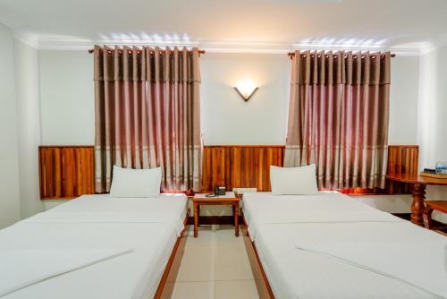 a room with two beds and a clock on the wall at Holiday Hotel in Kampong Speu