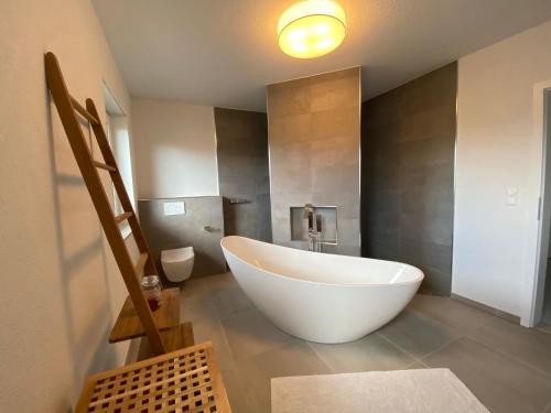 uma grande banheira branca numa casa de banho com WC em furnished & equipped TDY-TLA-TLF House-A - vollständig ausgestattetes Ferienhaus em Bruchmühlbach-Miesau