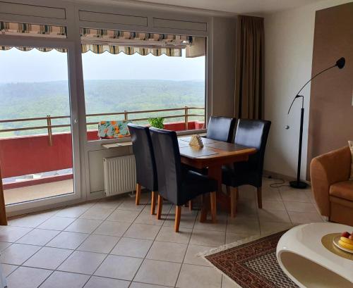 Un comedor con mesa y sillas y una gran ventana. en Ferienwohnung Sonnenschein mit Pool und Sauna, en Lahnstein